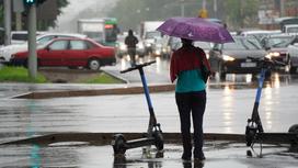 Женщина стоит возле дороги с зонтом