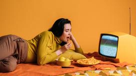 Девушка ест ужин перед телевизором