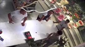 Мужчина, находясь в цветочном магазине, берет в руки ножницы