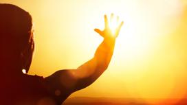 Человек направляет руки к солнцу