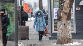 Женщина в голубой куртке идет по улице