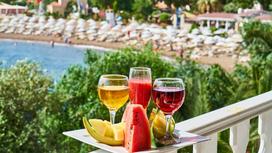 Напитки и фрукты стоят на подносе на фоне пляжа