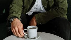 Мужчина сидит за столиком в заведении и пьет кофе