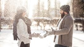 Мужчина и женщина обсыпают друг друга снегом