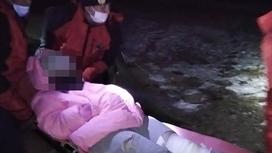 Спасатели несут на носилках девушку с поврежденной ногой