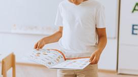Мальчик держит учебник