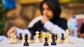 Молодой парень сидит возле шахматной доски