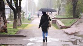 Женщина с зонтом идет по улице в дождливую погоду