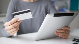 Женщина держит кредитную карту и планшет