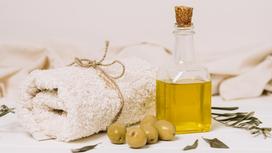 Оливковое масло в стеклянной бутылке, оливки и полотенце