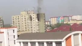 Черный дым идет из окна дома в Алматы