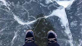 Человек в ботинках стоит на треснувшем льду