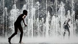 Люди спасаются от жары в фонтане