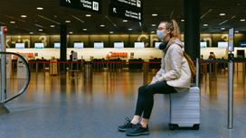 Девушка сидит на чемодане в аэропорту
