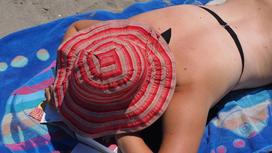 Женщина в шляпе загорает на солнце