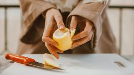 Женщина очищает лимон от кожуры