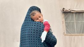 Женщина держит ребенка в Рафахе