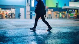 Мужчина идет по улице под дождем вечером