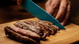 Мужчина режет ножом мясо
