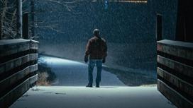 Мужчина стоит на темной улице зимой