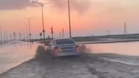 Машина едет по затопленной улице в Астане