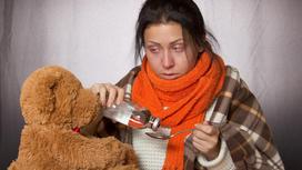 Девушка пьет лекарство рядом с игрушечным медведем