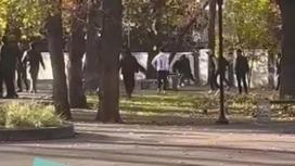 Фиуры бегущих и дерущихся людей между деревьями в городе