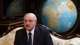 Александр Лукашенко сидит на фоне глобуса