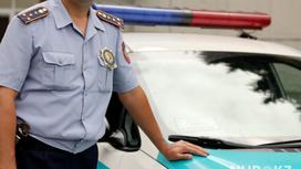 полицейский в форме стоит возле служебного автомобиля