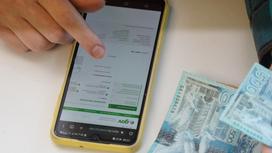 Женщина держит в руках деньги и пользуется смартфоном Женщина держит в руках деньги и пользуется смартфоном