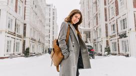 Девушка в сером пальто на заснеженной улице