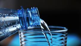Воду наливают в стакан из бутылки