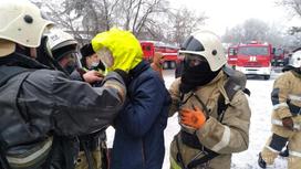 Пожарные стоят вокруг мужчины на фоне спецтехники