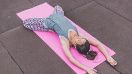 Девушка лежит на коврике для йоги