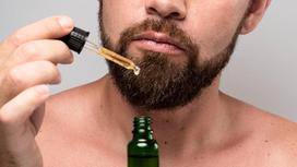 Мужчина с густой бородой держит бутылек с репейным маслом