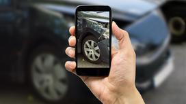 Мужчина фотографирует застрахованный автомобиль Мужчина фотографирует застрахованный автомобиль