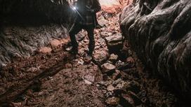 Мужчина стоит в шахте и светит фонариком