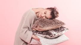 Женщина в свитере держит в руках три декоративные подушки. Подушки сделаны из старых свитеров и джемперов