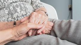 Женщина держит пожилую женщину за руку