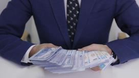 Мужчина в костюме держит в руках крупную сумму денег