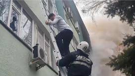 Пожарный помогает мужчине спуститься по лестнице