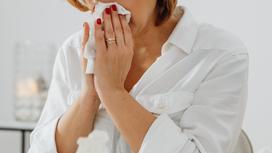 Женщина вытирает нос платком