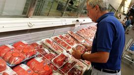Мужчина выбирает мясо в супермаркете