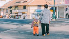 Бабушка идет по улице с внуком