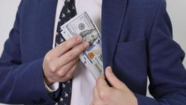 Мужчина кладет в карман пачку долларов Мужчина кладет в карман пачку долларов