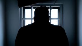 Мужчина стоит возле окна в тюрьме