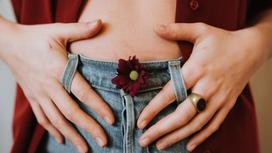Девушка держится за джинсы с цветком