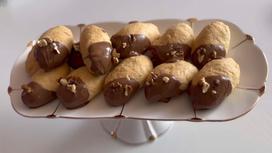 На сервировочной тарелке песочное печенье с декором из шоколада и орехов