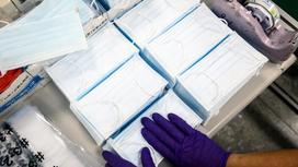 Медицинские маски упаковывает работник в перчатках