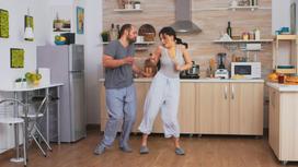 Мужчина и женщина в домашней одежде танцуют на кухне